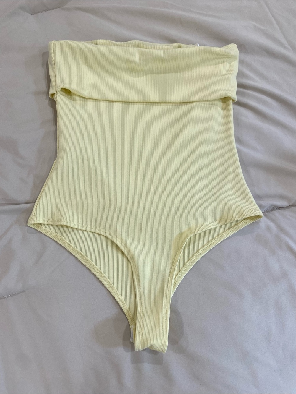 Pale yellow strapless body suit. Never worn. Size small